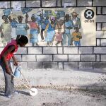 Una menor haitiana juega en una céntrica calle de Puerto Príncipe delante de un cartel de Oxfam, ONG que tapó abusos de sus trabajadores y la contratación de prostitutas en el país caribeño tras el terremoto de 2010