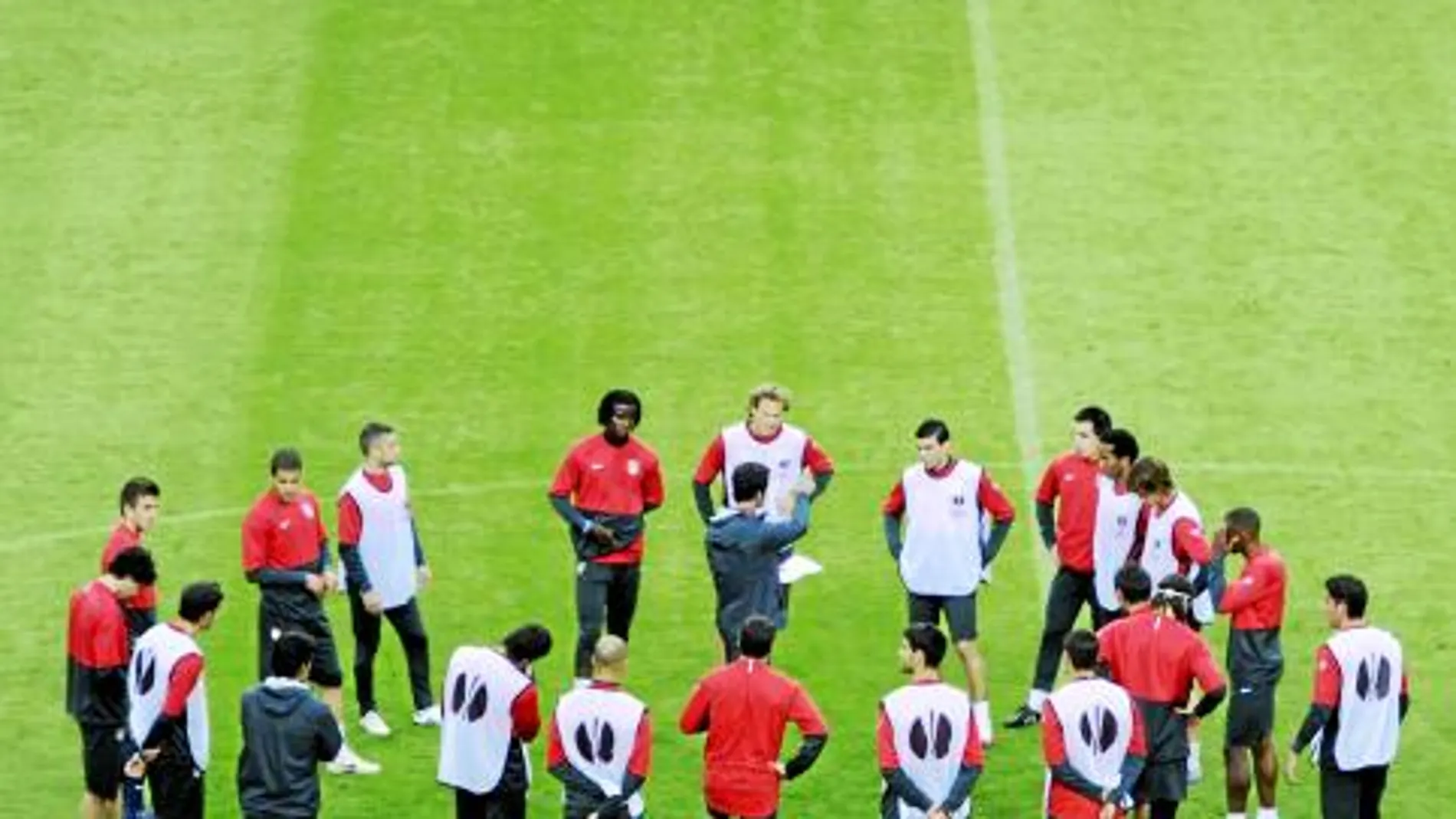 Quique habla con sus futbolistas sobre el césped durante una sesión de trabajo del Atlético de Madrid