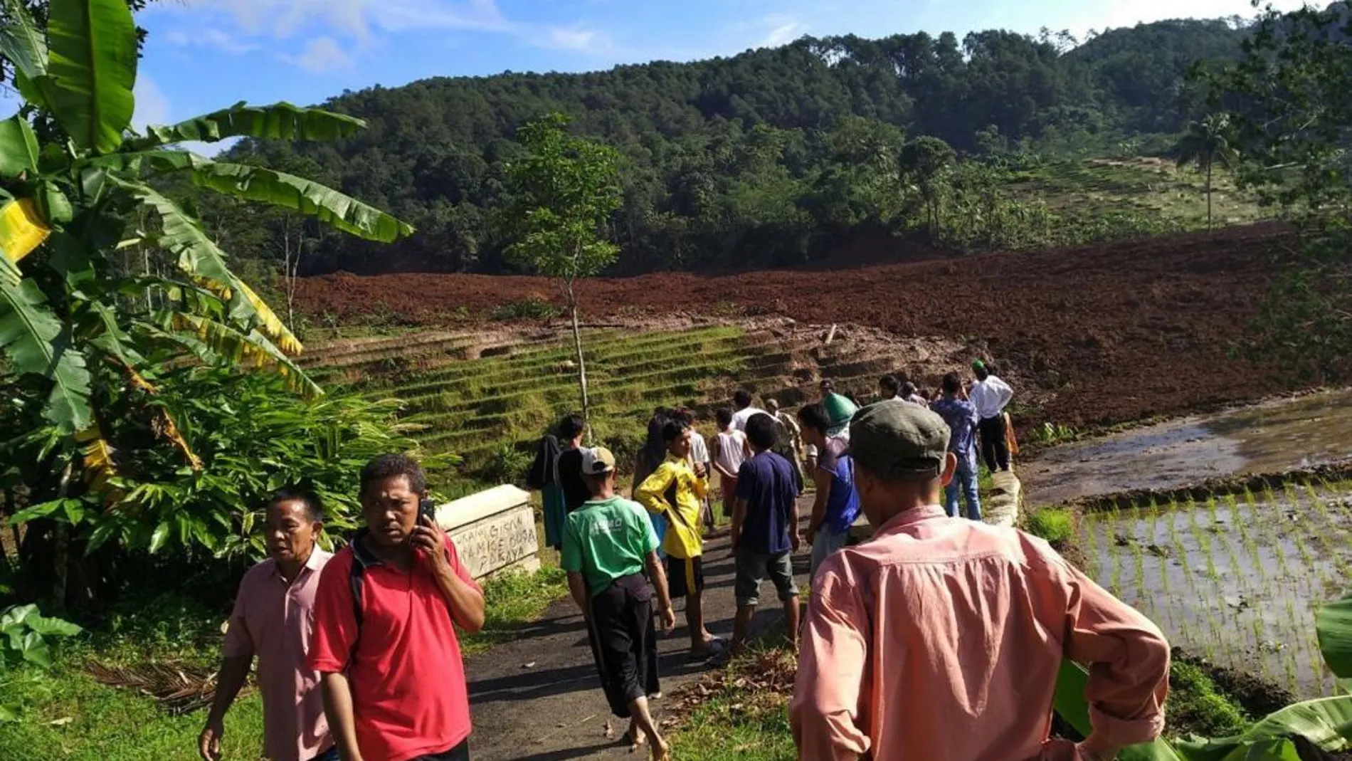 Varias personas permanecen cerca del lugar donde se produjo un alud de tierra en Brebes, en la isla indonesia de Java, hoy