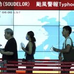 Pasajeros caminan junto a una pantalla que muestra la evolución del tifón Soudelor antes de embarcar en su vuelo en el aeropuerto Internacional de Taoyuan, taiwán.