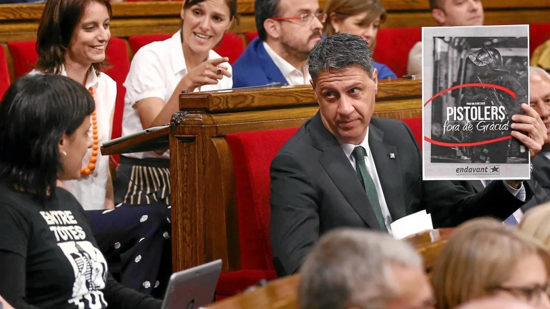 Albiol mostró ayer en el Parlament un cartel de Endavant (una organización integrada en la CUP) en el que se acusa a los Mossos d’Esquadra de «Pistoleros». «Fuera de Gràcia», se puede leer también