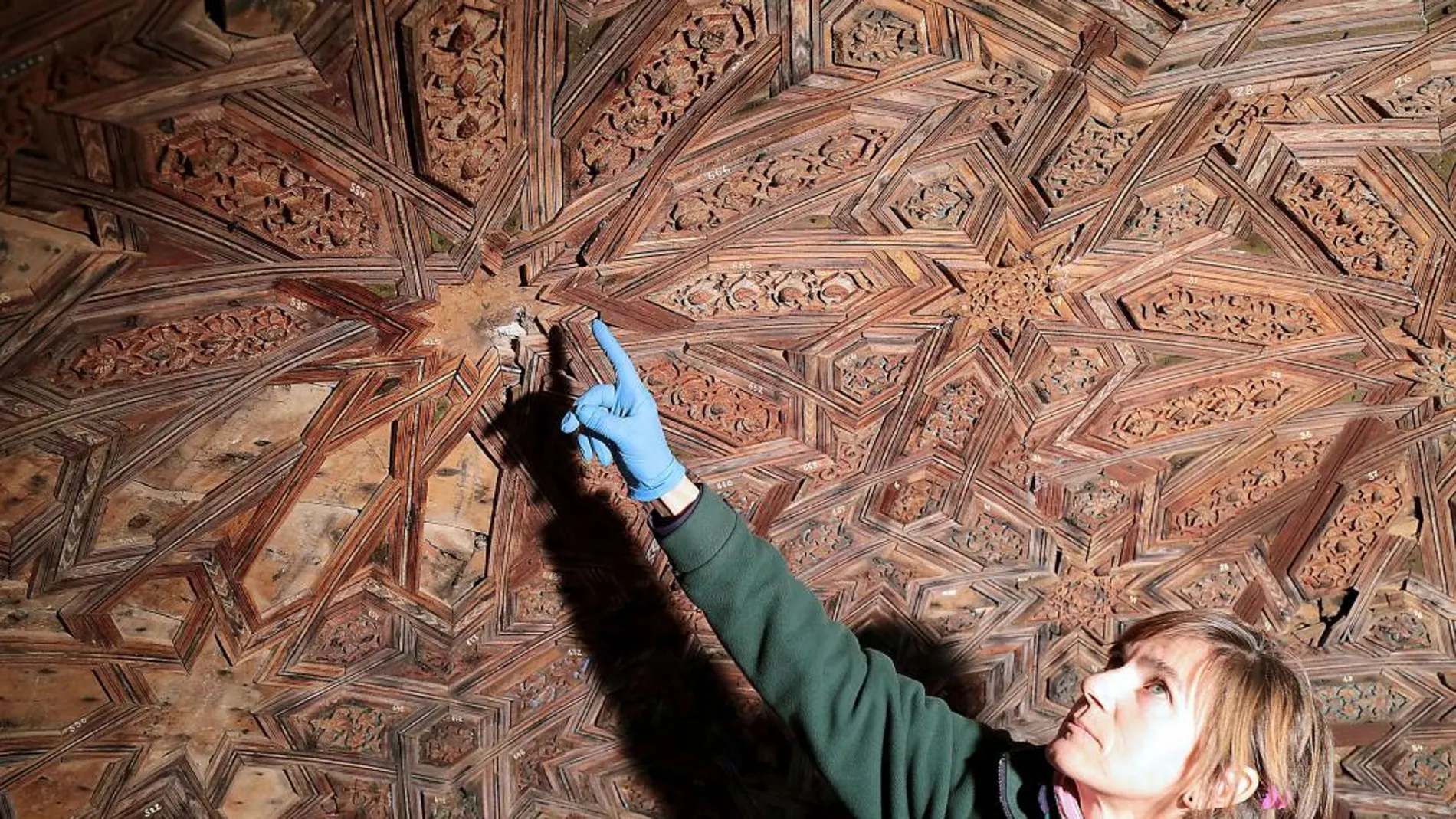 Una restauradora señala las piezas de madera que conforma la cúpula del templete oeste del Patio de los Leones de la Alhambra de Granada