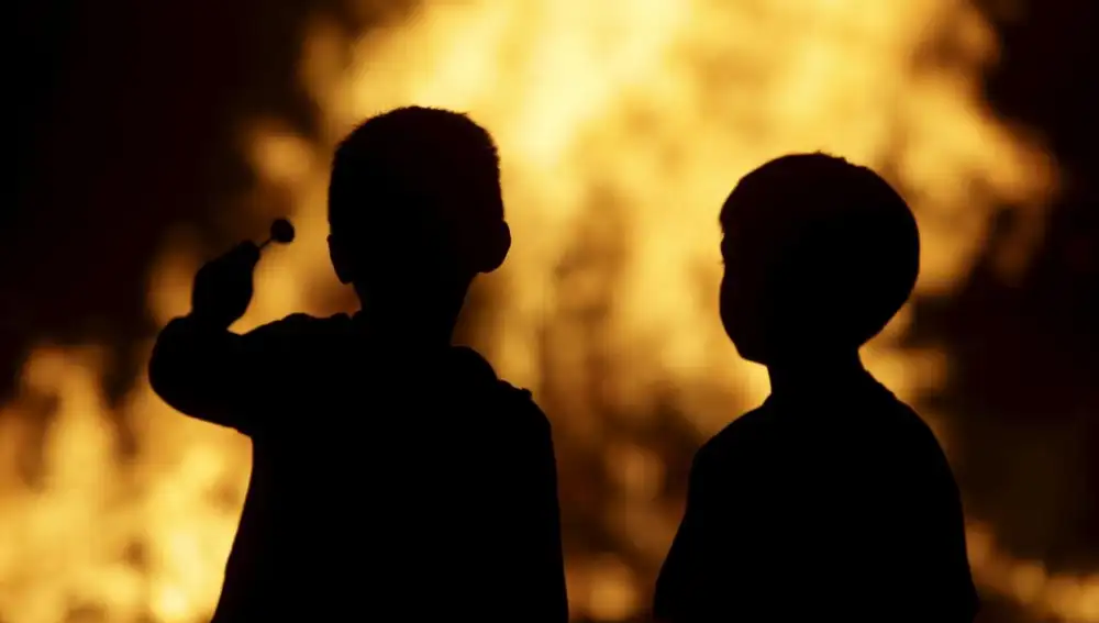 En la imagen, dos niños frente a las hogueras de las fiestas de San Juan | Imagen de archivo