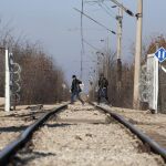 Dos refugiados cruzan las vías de un tren en la localidad de Idomeni, Grecia el 21 de enero de 2016 desde donde partirán a Macedonia.