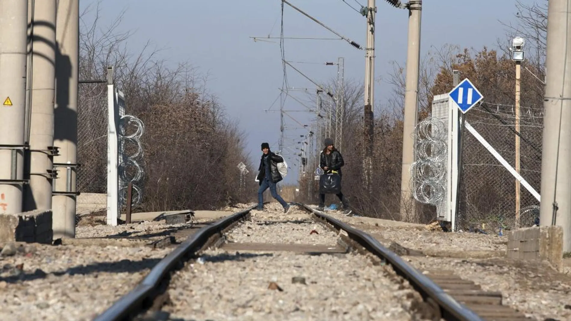 Dos refugiados cruzan las vías de un tren en la localidad de Idomeni, Grecia el 21 de enero de 2016 desde donde partirán a Macedonia.