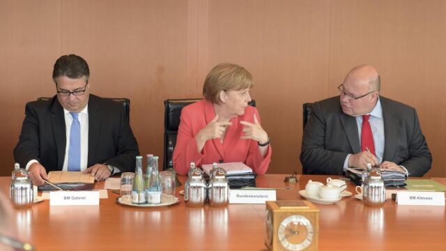 La canciller alemana, Angela Merkel (centro), habla con el jefe de la cancillería, Peter Altmaier (dcha), junto a su ministro de Economía, Sigmar Gabriel.