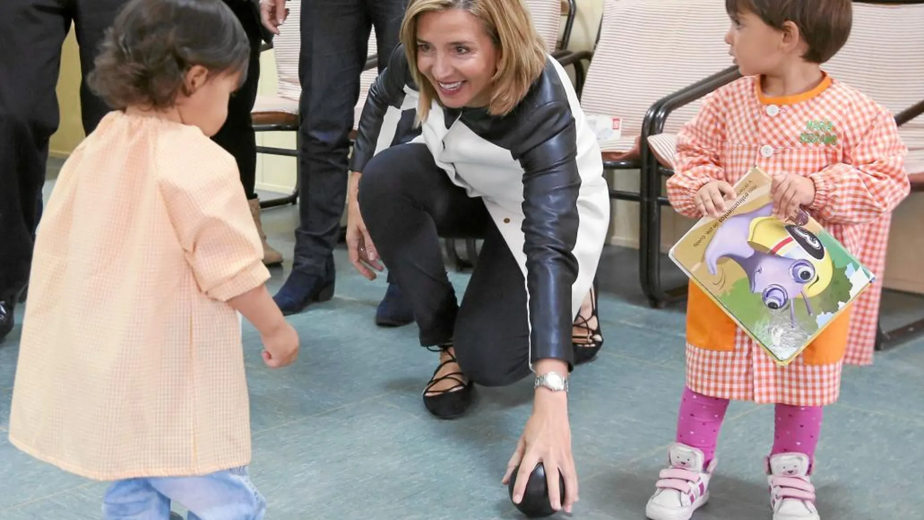 La consejera de Familia, Alicia García, juega con dos niños durante su visita al centro infantil «Alborada» de Olmedo