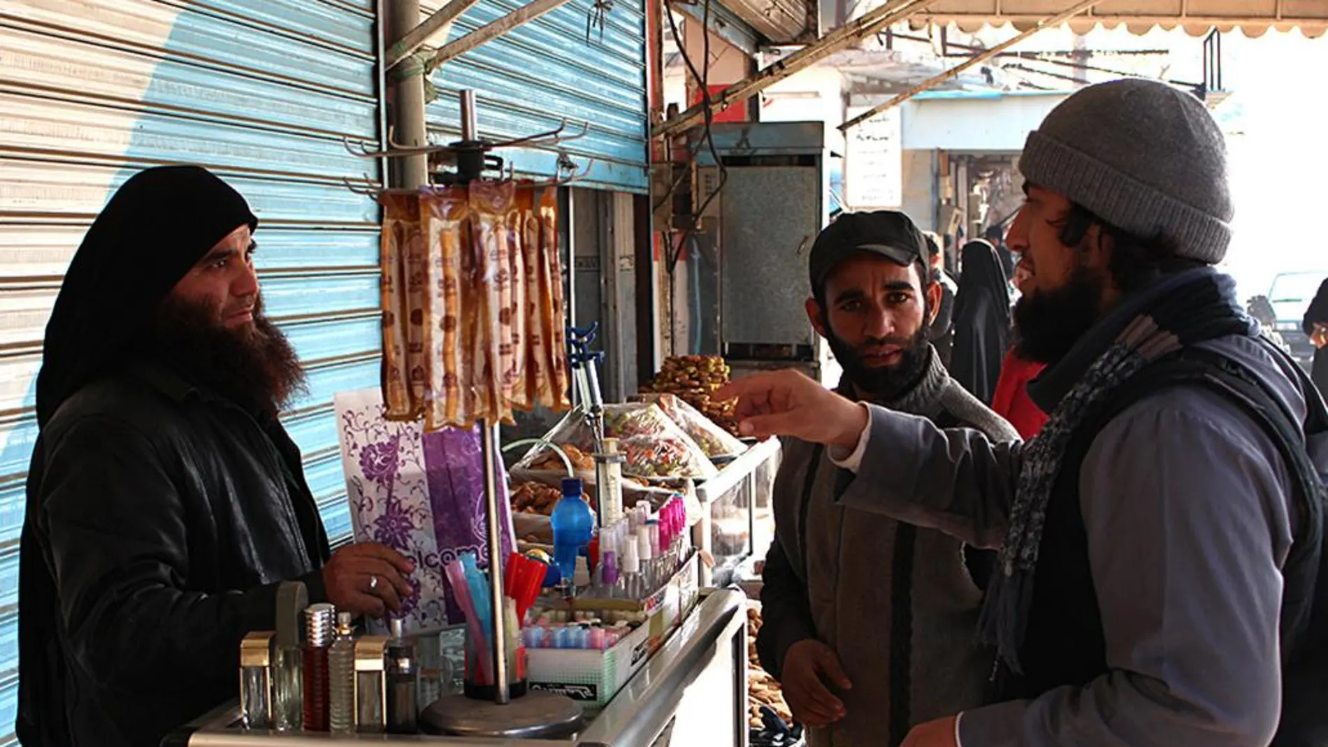 Miembros del Estado Islámico hablan con un vendedor en una calle de Raqqa, Siria