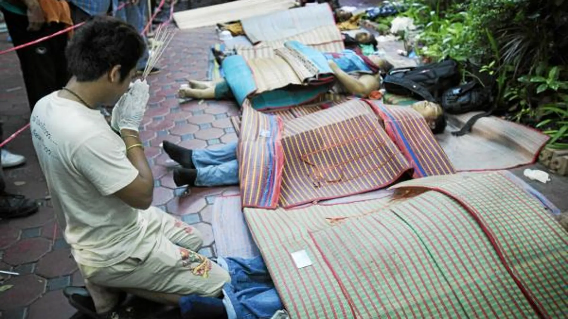 Un hombre reza frente a los cuerpos de los «camisas rojas» muertos en los enfrentamientos de Bangkok