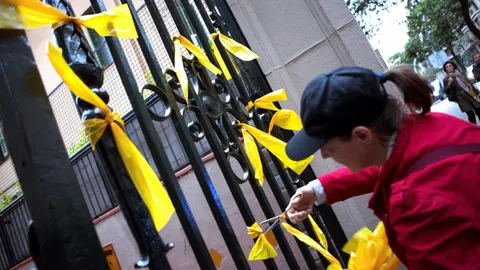 Una joven retira de los Grupos de Defensa y Resistencia (GDR), contrarios a la independencia de Cataluña, retirando lazos amarillos