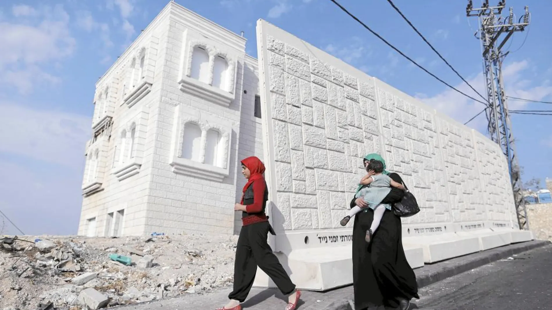 Mujeres palestinas frente a un muro temporal de hormigón en el barrio de Yabel Mukaber, en Jerusalén Este