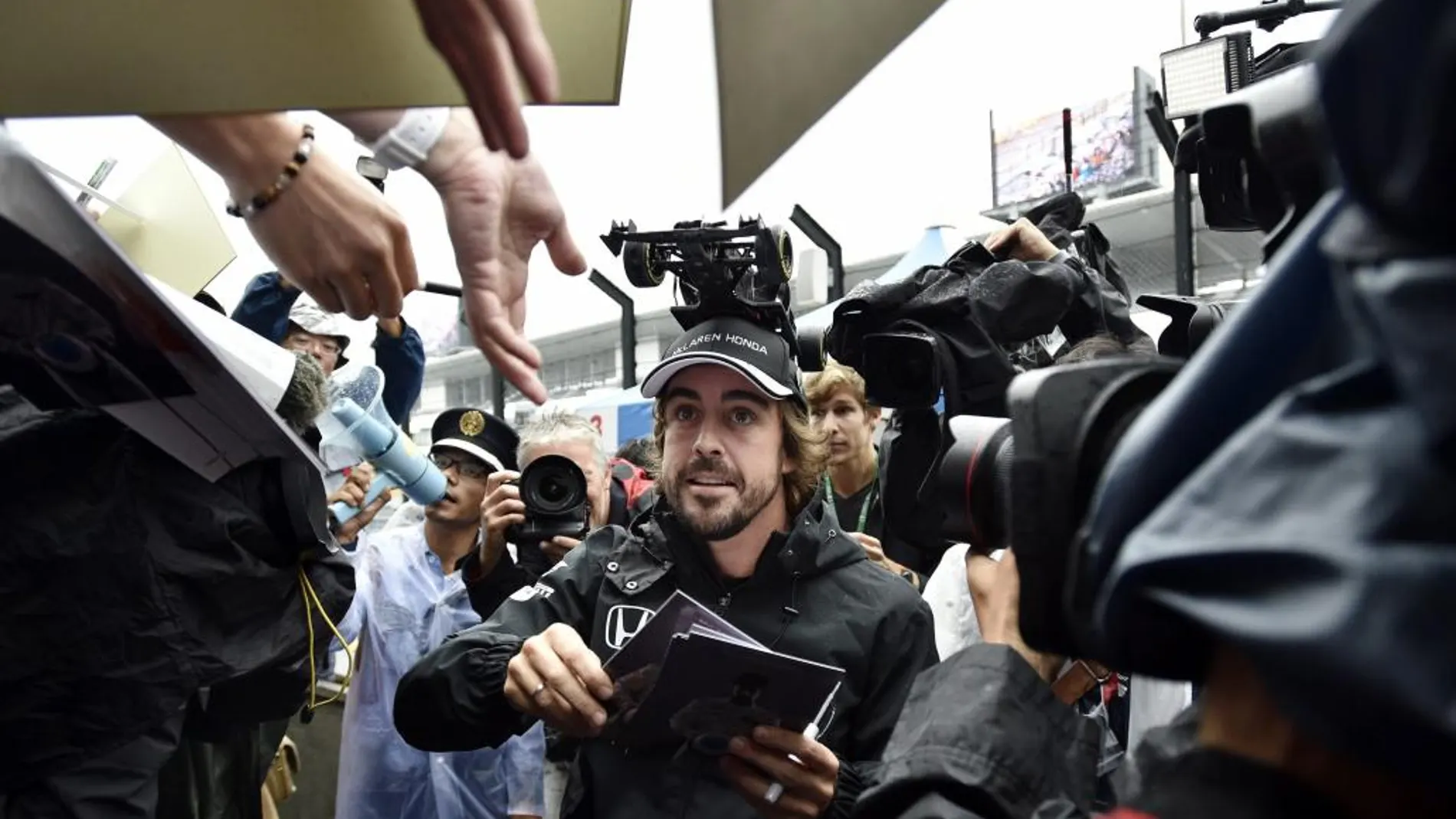 El piloto español de Fórmula Uno Fernando Alonso reparte autógrafos a sus fans en el circuito de Suzuka en Japón