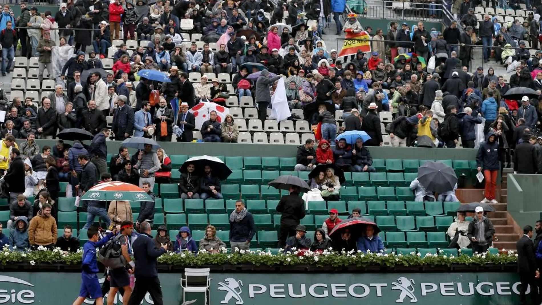 El tenista español David Ferrer (2i) sale de la pista tras suspenderse ayer su partido frente al checo Tomas Berdych