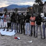 El imán Sami Bubaki dirige la oración de un grupo de inmigrantes en la playa de Ventimiglia tras la puesta de sol