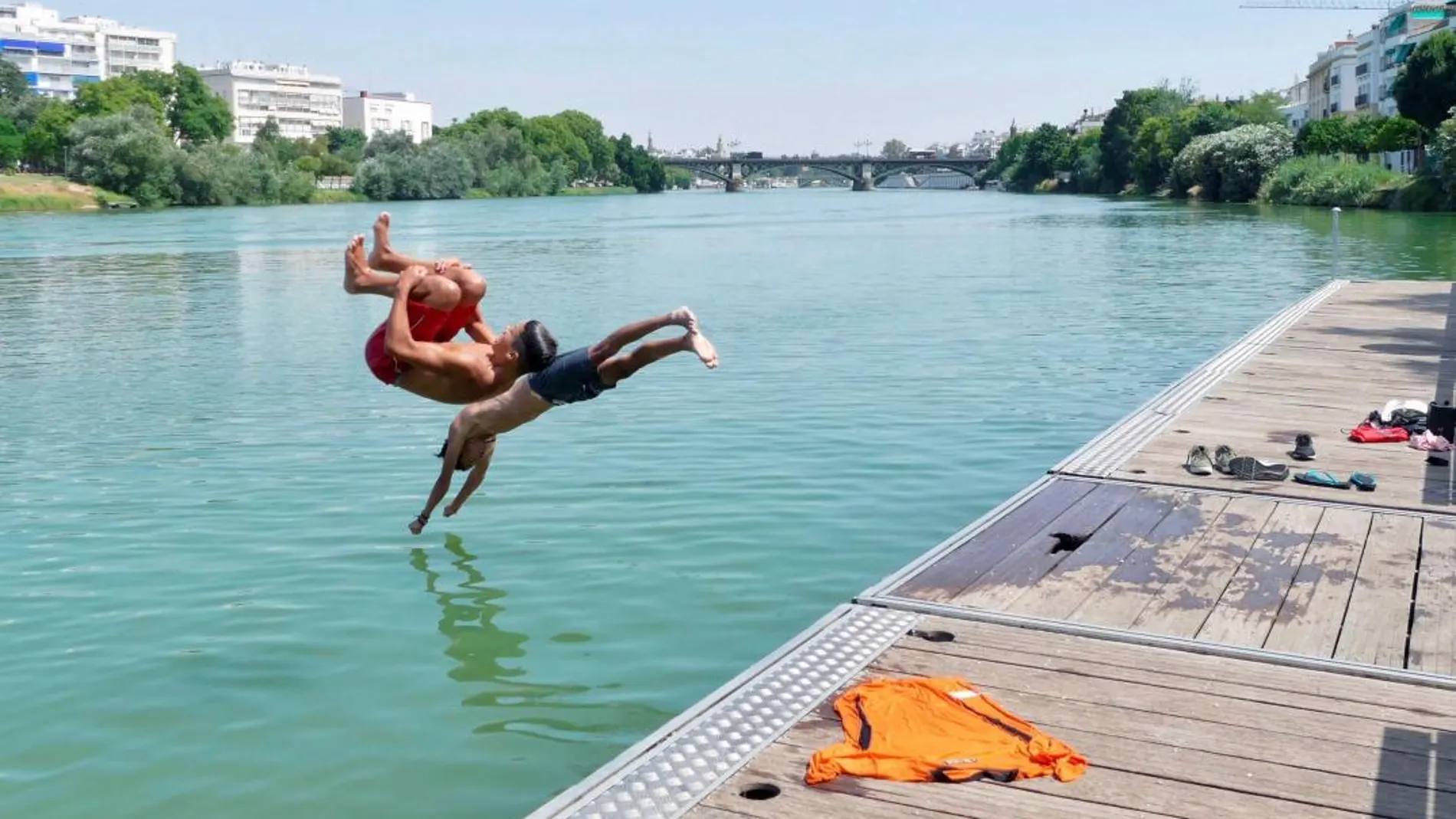 Dos jóvenes se lanzan al río Guadalquivir hoy en Sevilla, una de las ciudades más afectadas por la fuerte ola de calor que está provocando temperaturas récord estos días. /Foto: Efe