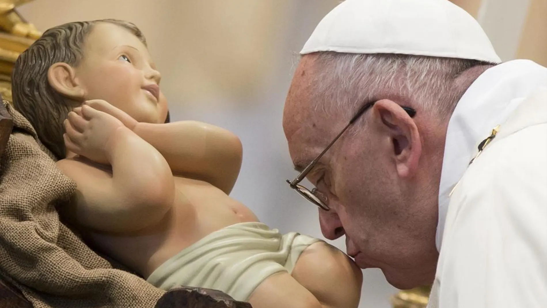 El Papa Francisco besa una figura del niño Jesús antes de presidir la Santa Misa