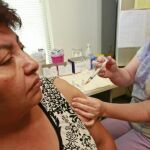 Una enfermera vacuna a una mujer contra gripe estacional