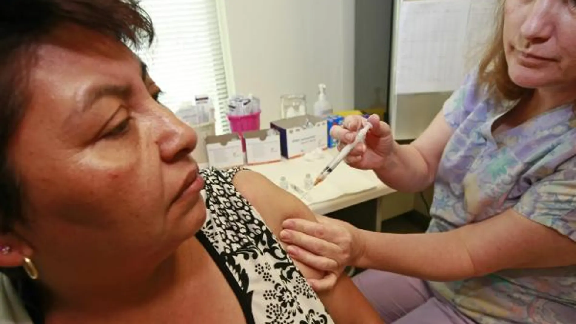 Una enfermera vacuna a una mujer contra gripe estacional