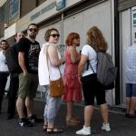 Atenienses hacen cola para retirar dinero de un cajero automático en una sucursal del Banco Nacional de Grecia, en Atenas