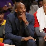 El jugador de los Lakers de Los Ángeles Kobe Bryant (izq, de traje) observa desde el banquillo el partido de la NBA de baloncesto que los Lakers disputan contra los Mavericks de Dallas en Los Ángeles, California ayer 26 de enero de 2016