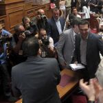 El primer ministro griego, Alexis Tsipras (c), aplaudido por sus compañeros a su llegada a una reunión del grupo parlamentario de Syriza .