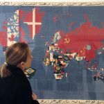 Una mujer observa la obra "Mapa -Traer al mundo el mundo"(1984), de Alighiero Boetti