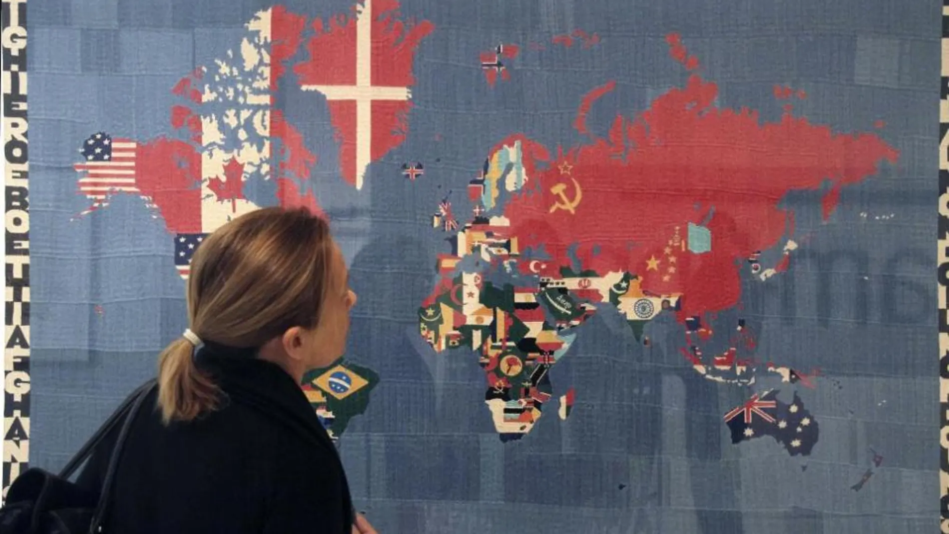 Una mujer observa la obra "Mapa -Traer al mundo el mundo"(1984), de Alighiero Boetti