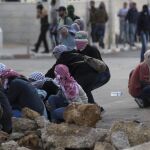 Palestinos se ponen a cubierto durante un enfrentamiento con el Ejército israelí en Ramala