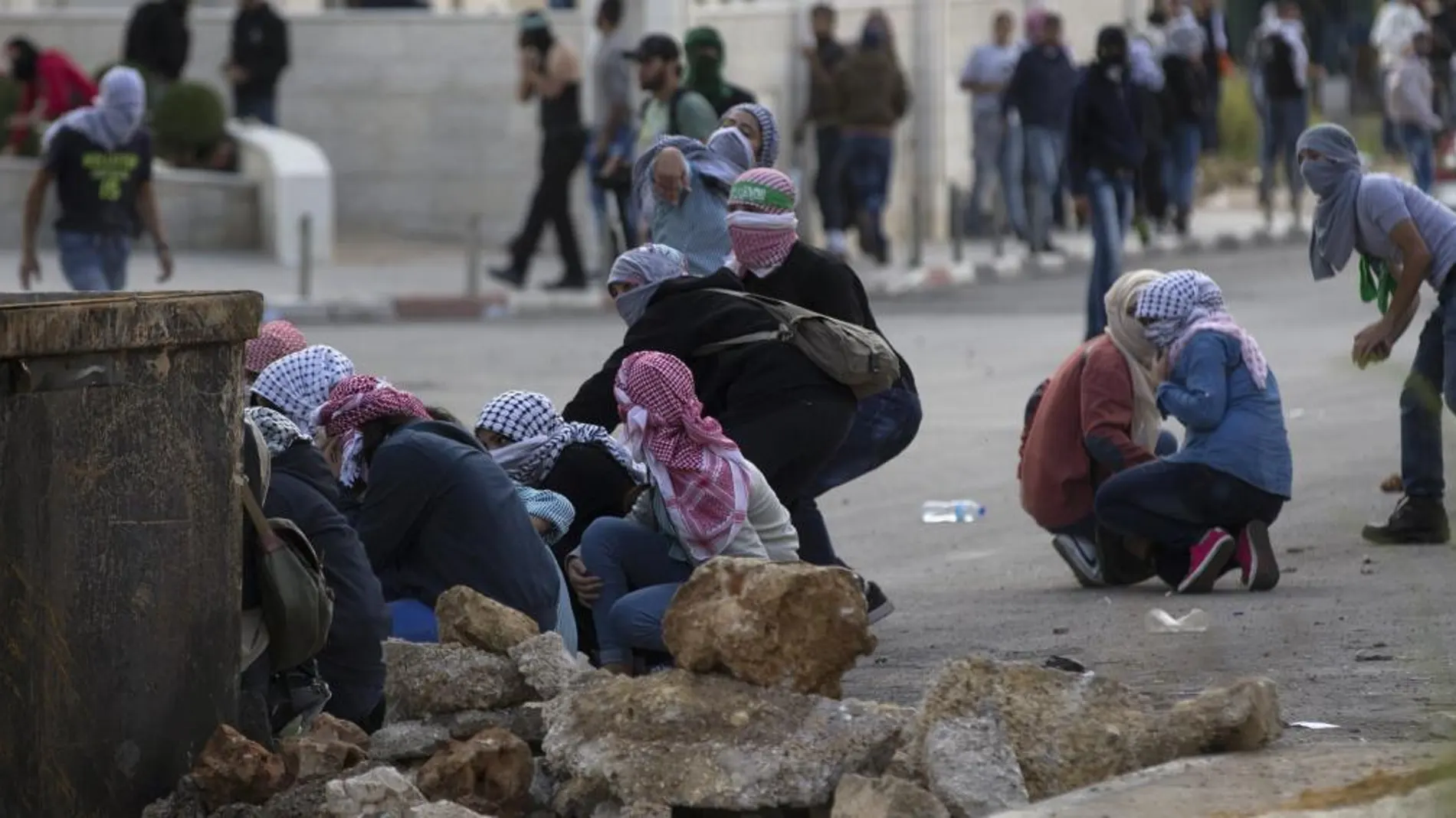 Palestinos se ponen a cubierto durante un enfrentamiento con el Ejército israelí en Ramala