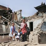 Una madre pasa con sus hijas por unas casas destruidas por el terremoto