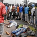 Un grupo de hombres observa los cadáveres de dos simpatizantes de Ouattara asesinados durante los recientes disturbios en Abiyán