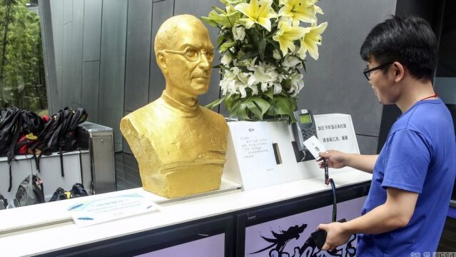 Un empleado registra su entrada ante la férrea mirada del busto de Jobs