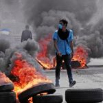 Un joven camina junto a varios neumáticos ardiendo en una calle de Nicaragura durante las protestas