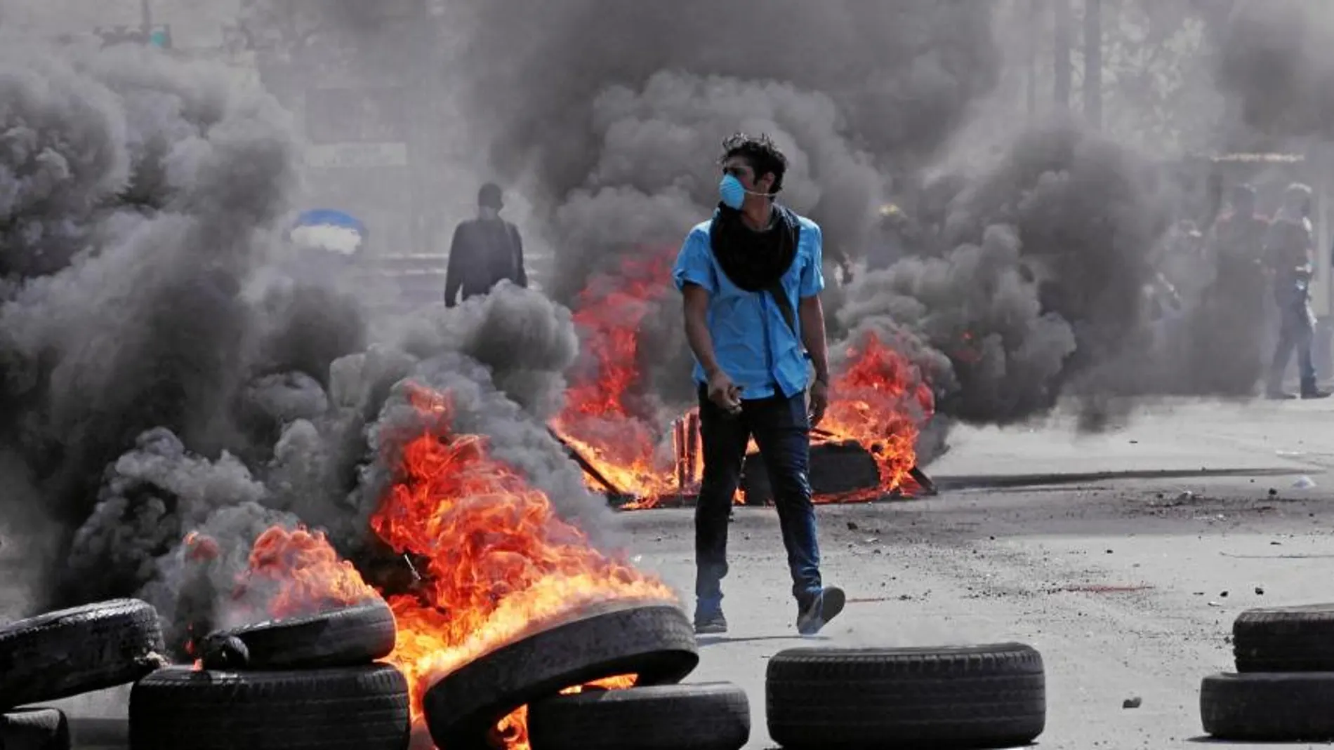 Un joven camina junto a varios neumáticos ardiendo en una calle de Nicaragura durante las protestas