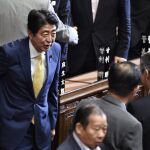 El primer ministro nipón, Shinzo Abe (izq), conversa con varios diputados tras la votación