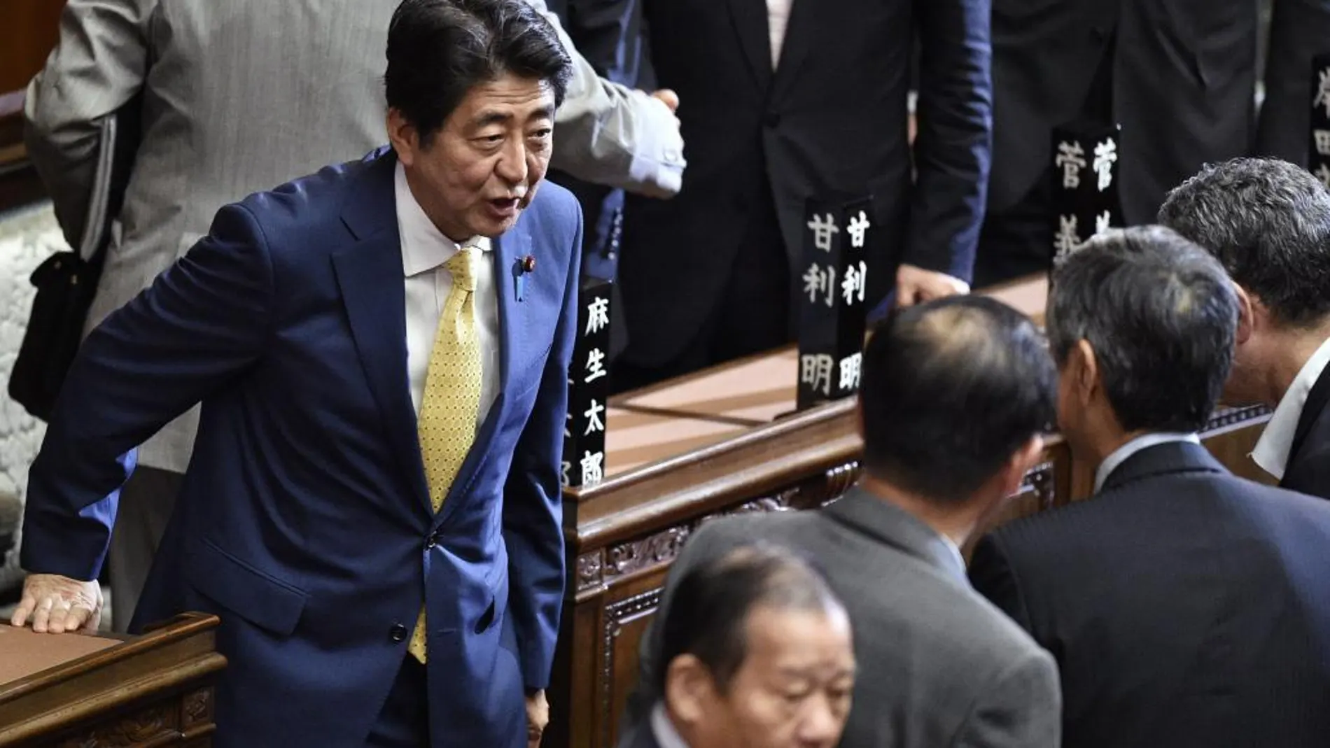 El primer ministro nipón, Shinzo Abe (izq), conversa con varios diputados tras la votación