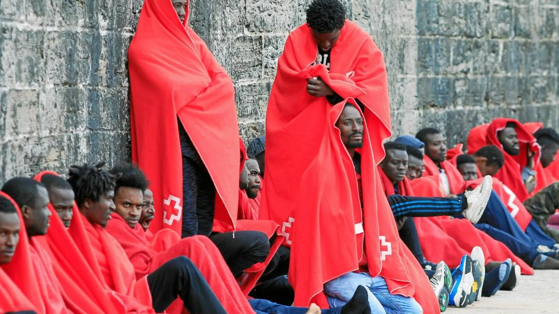 Inmigrantes protegidos con mantas de Cruz Roja esperan a ser atendidos en el puerto de Tarifa (Cádiz)