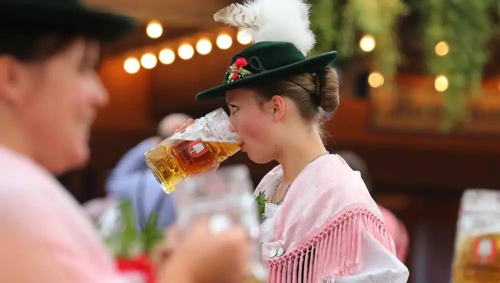 Una mujer, con el tradicional traje bábaro, bebe una cerveza en la Oktoberfest en Munich.