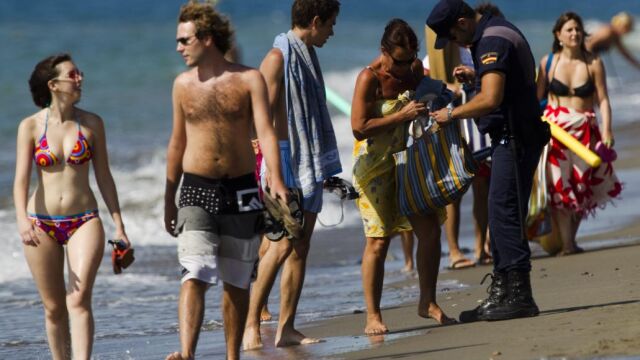 Un policía nacional inspecciona el bolso de un bañista