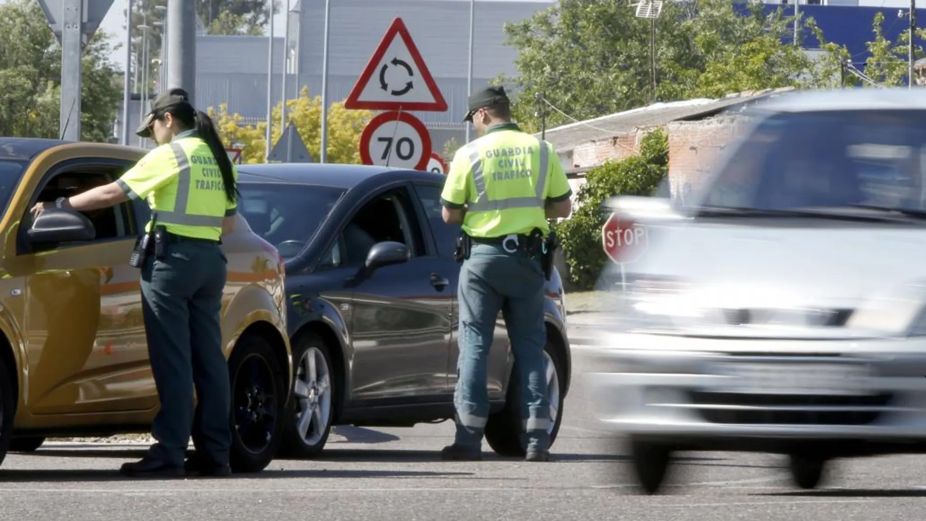 Agentes de la Guardia Civil de Tráfico piden la documentación a los conductores de algunos vehículos.