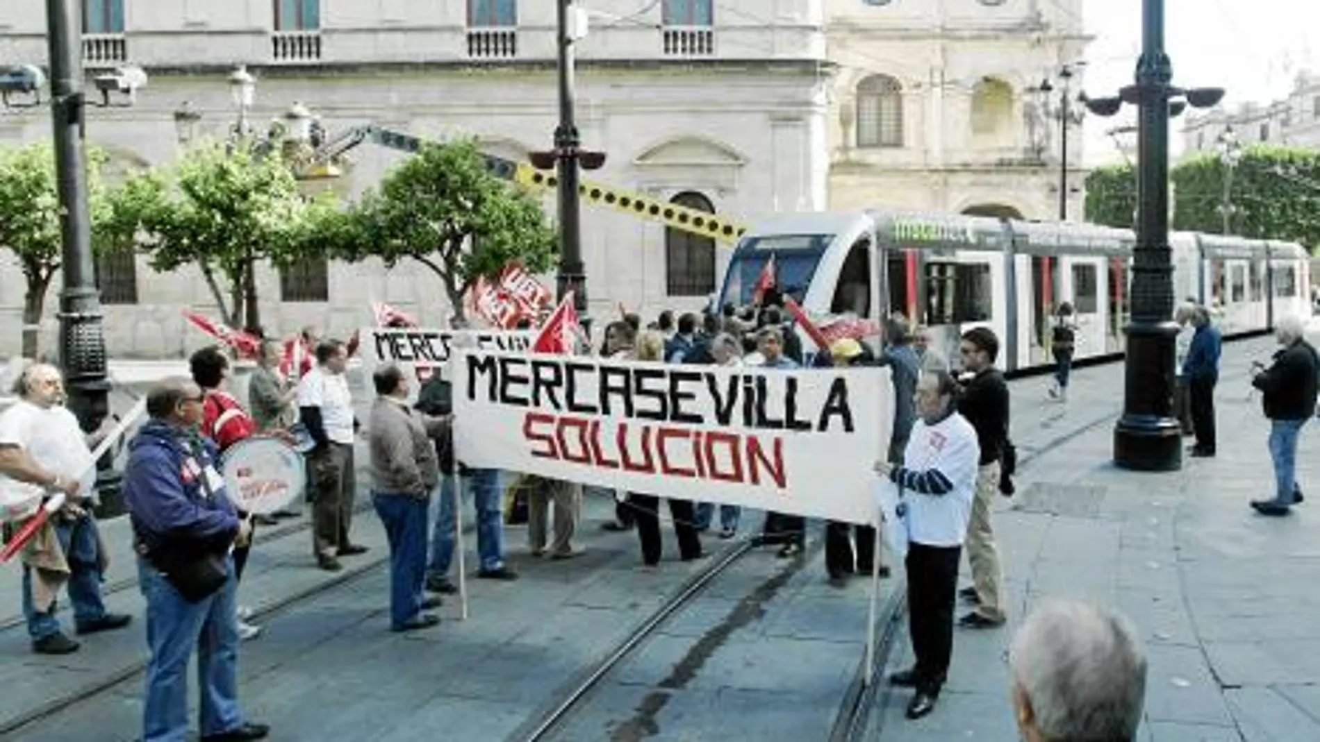 Los manifestantes despliegan una pancarta al paso del tranvía