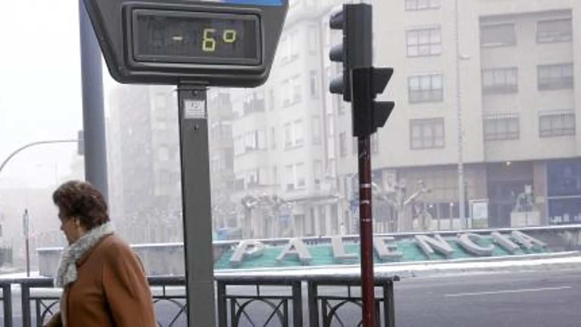 Una mujer huye del frío imperante en la gélida mañana de ayer, que helaba la fuente en la que está impreso el nombre de Palencia