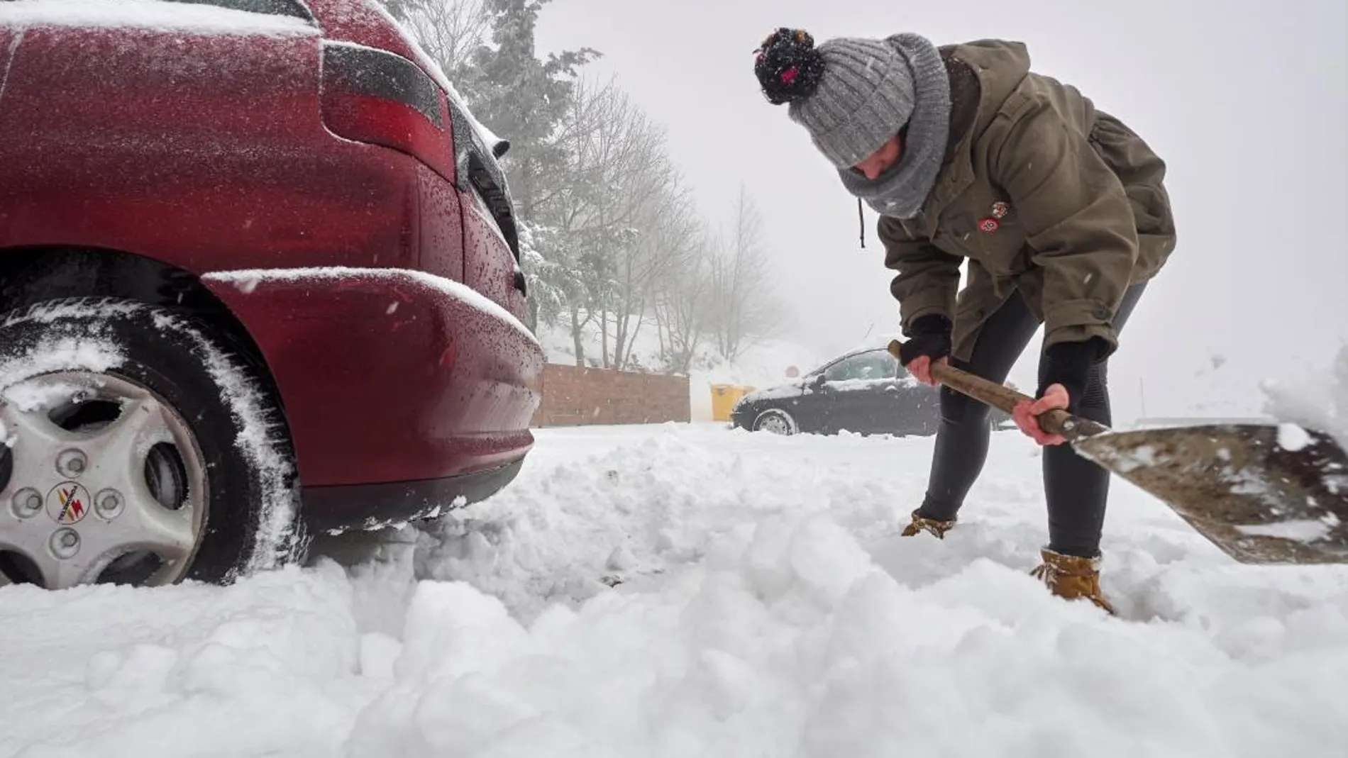 Una joven retira la nieve acumulada tras la nevada copiosa caída de madrugada en Galicia. EFE/EliseoTrigo