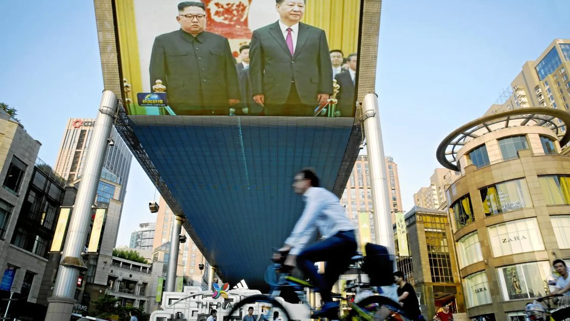 Un ciclista pasa ayer frente a una pantalla gigante emitiendo la visita de Kim Jong Un a Xi Jinping