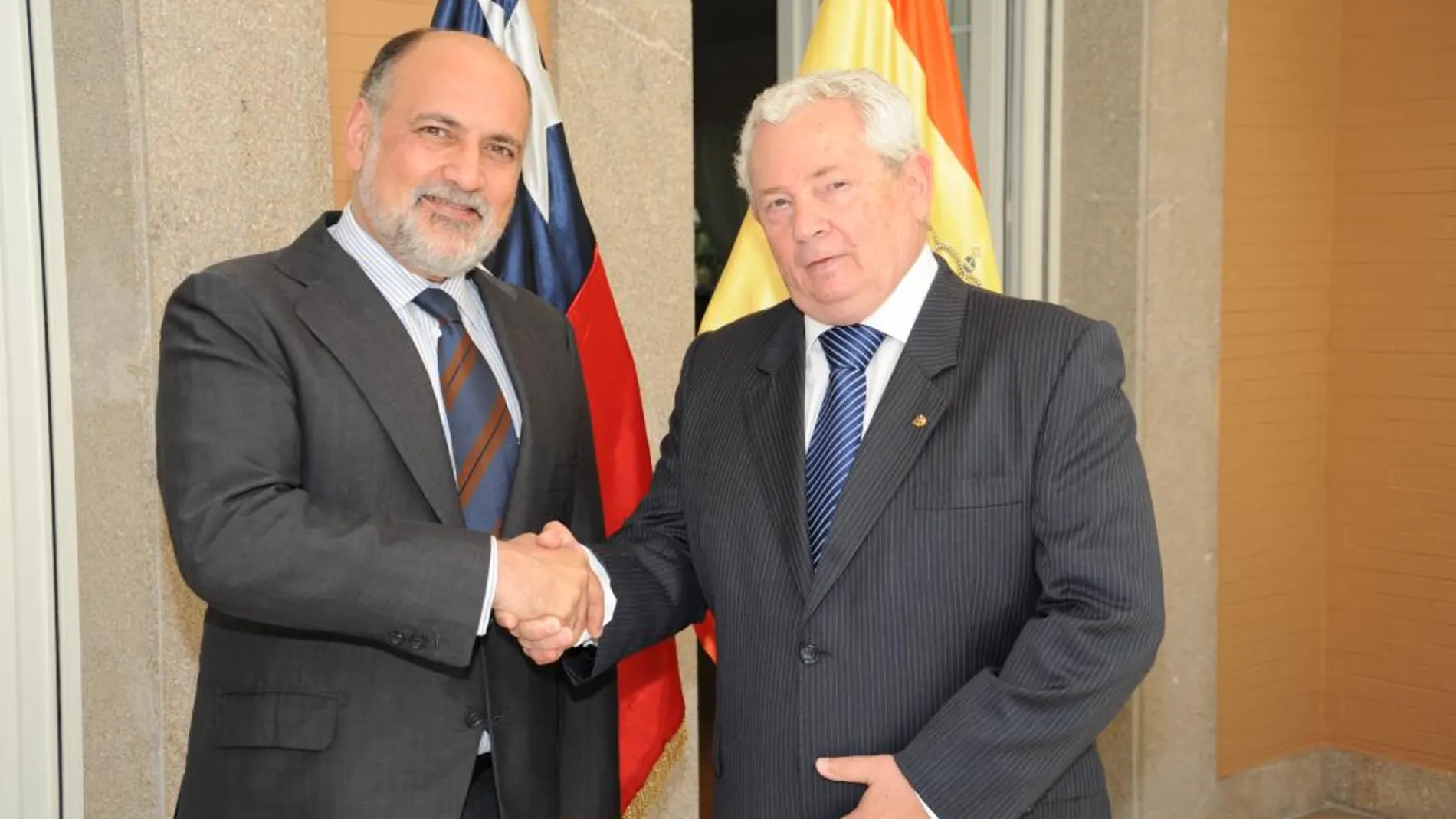 El presidente del Tribunal Constitucional Francisco Pérez de los Cobos, presenta el saludo protocolario al embajador chileno Francisco Marambio Vial, delante de las banderas de ambos países.