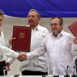 El delegado de las FARC en Cuba, Rodrigo Londoño Echeverri, alias "Timochenko"(d) y el presidente de Colombia, Juan Manuel Santos (i) junto a el presidente de Cuba, Raúl Castro (c) sostienen en sus manos el acuerdo de paz entre el Gobierno colombiano y las FARC, durante la ceremonia en La Habana (Cuba)