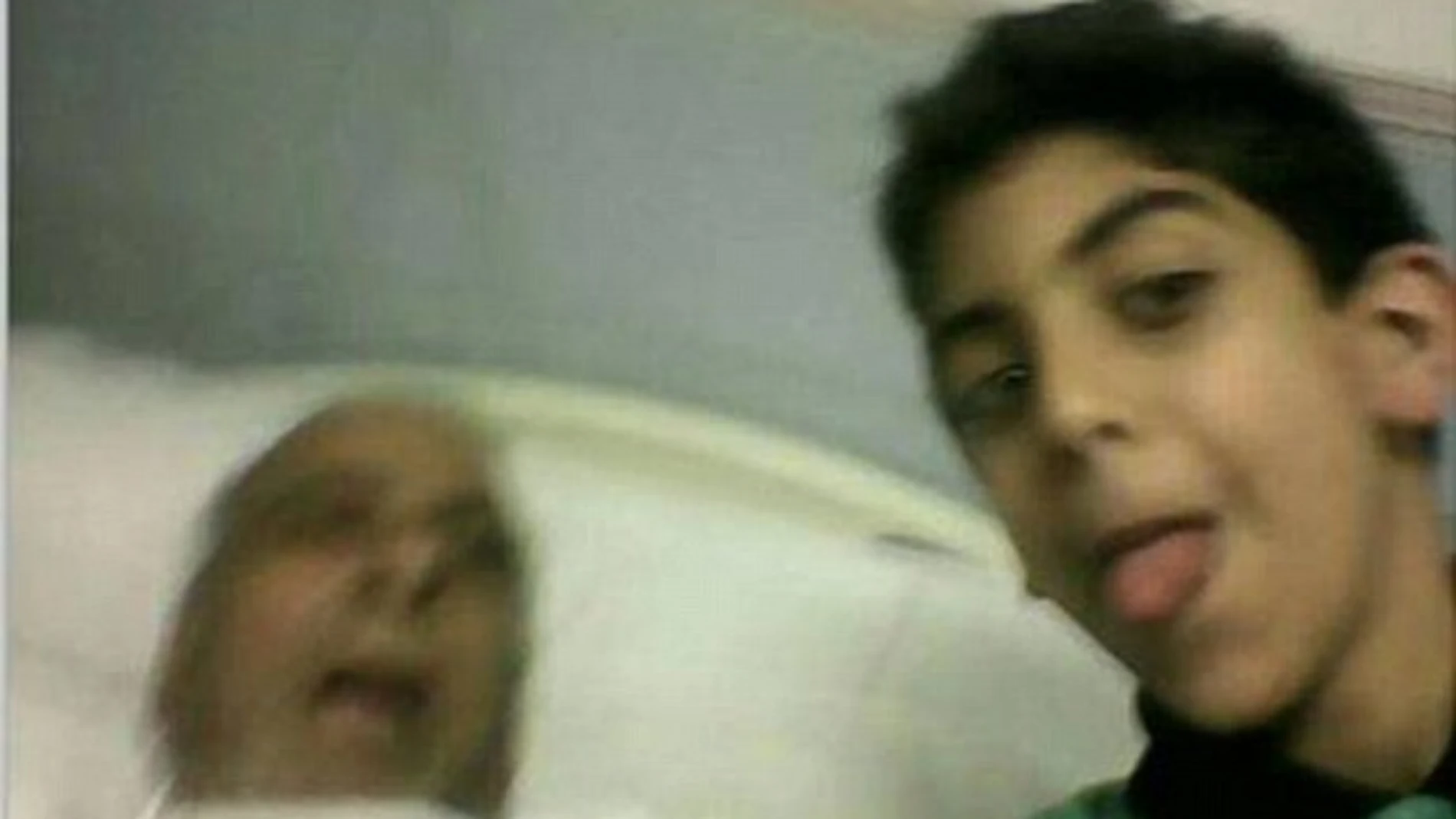 El joven saca la lengua para posar junto al cadáver de su abuelo