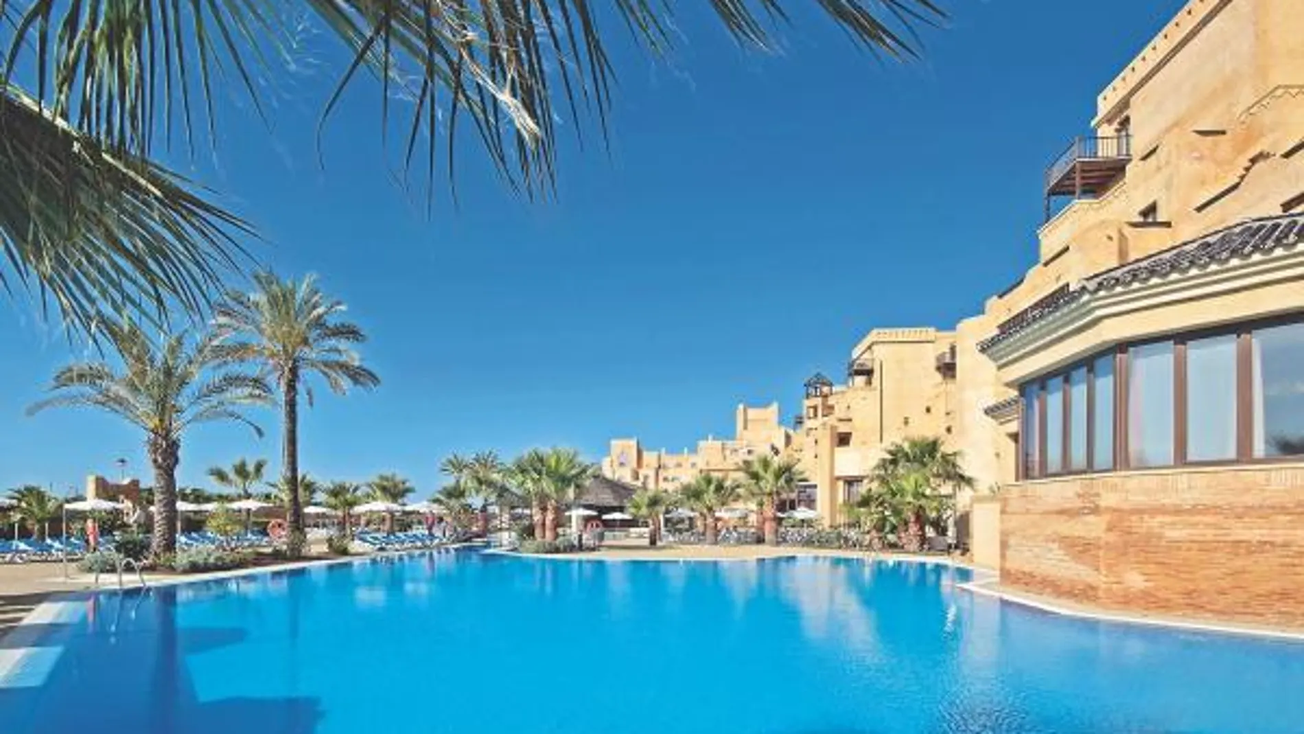 La amplia piscina exterior está rodeada de palmeras y de hamacas en las que resulta una delicia relajarse bajo el sol
