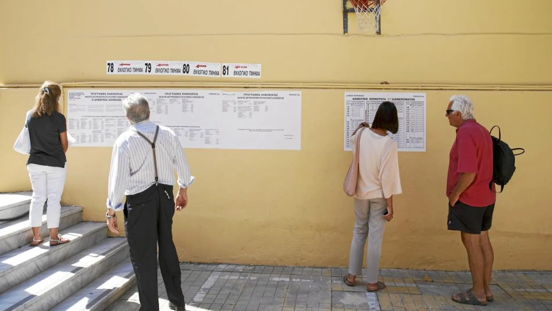 Varios votantes consultan el listado de mesas ayer en un colegio electoral del centro de Atenas