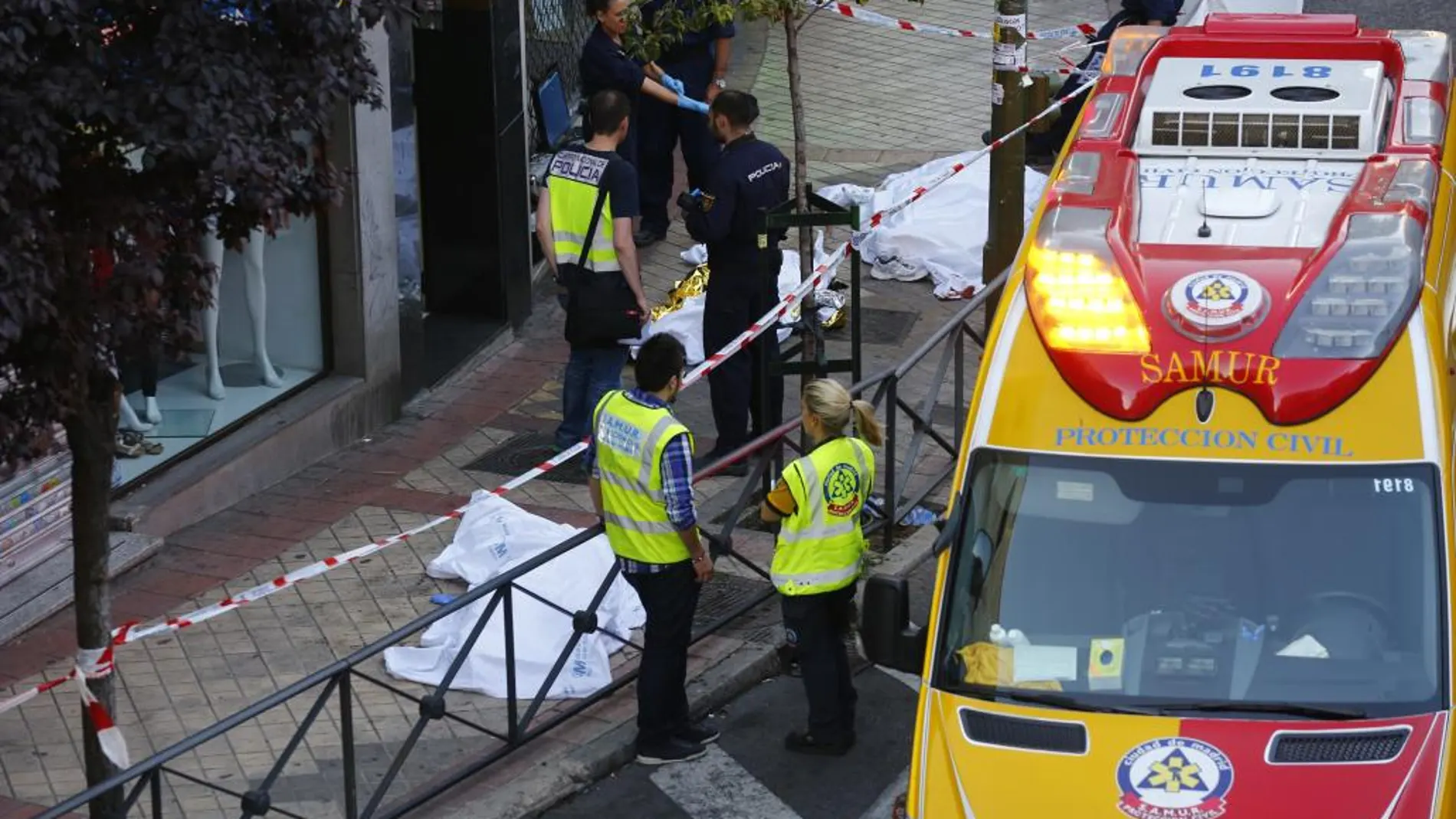 Imagen de los tres cuerpos cubiertos en la calle de Marcelo Usera, donde tuvo lugar el suceso.